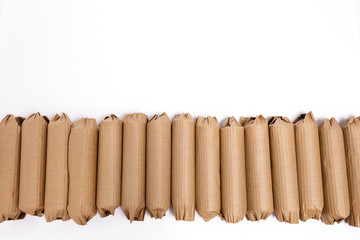Many cardboard wrapped cylindrical products in a horizontal row ready to be shipped against a white background.