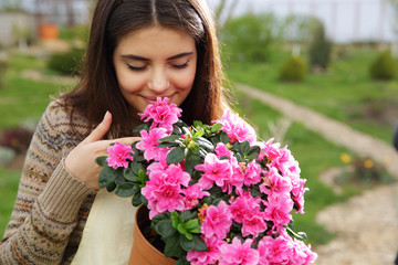 Naklejka premium Young woman smelling pink flowers in garden