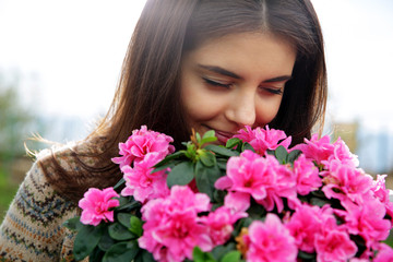 Naklejka premium Portrait of a young happy woman smelling pink flowers