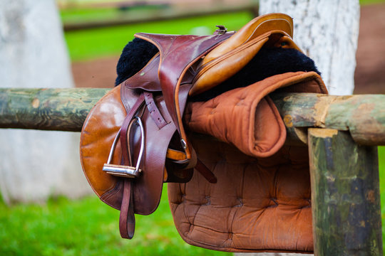 High-quality leather saddle for horse riding on a wooden fence