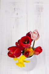 bouquet of tulips in a vase on a white wooden background
