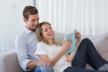 Relaxed couple reading book on couch