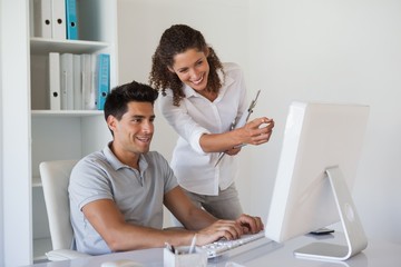 Casual business team looking at computer together at desk