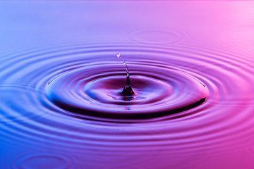Naklejka na ściany i meble Water drop close up with concentric ripples colourful blue and p
