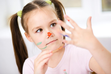 Portrait of a cute girl playing with paints