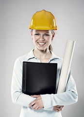 Woman constructor in helmet standing with project blueprints