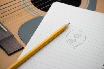 Note book and pen on the top of acoustic guitar