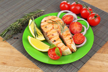 Tasty grilled salmon with vegetables, on wooden table