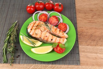 Tasty grilled salmon with vegetables, on wooden table