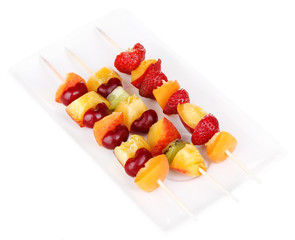 Mixed fruits and berries on skewers isolated on white