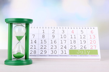 Hourglass and calendar on bright background