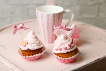 Tasty cup cakes with cream on wooden chair