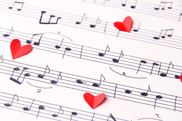 Red paper hearts on music book, close-up