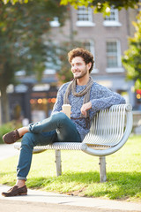 Obraz premium Man Relaxing On Park Bench With Takeaway Coffee