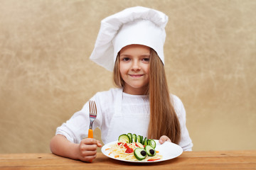 Happy child with chef hat and decorated pasta dish