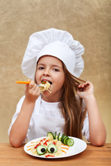 Happy chef child eating a creative pasta dish