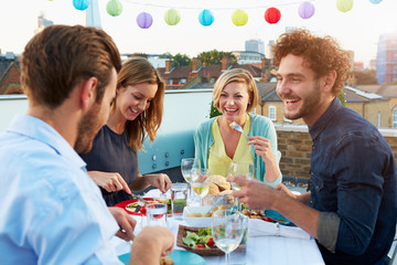 Group Of Friends Eating Meal On Rooftop Terrace