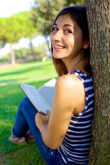 Naklejka premium Cute young woman reading book in park in the summer