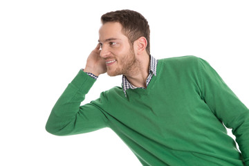 Junger Mann in Grün isoliert blickt lauschend zur Seite