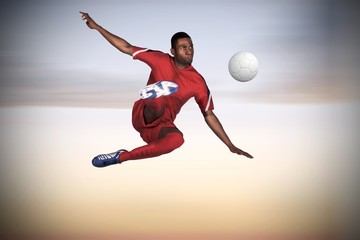 Naklejka premium Composite image of football player in red kicking