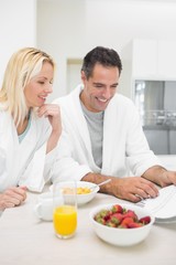 Obraz na płótnie Canvas Couple having breakfast while reading newspaper in kitchen