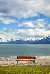 Naklejka na ściany i meble Old wooden bench at a lake with mountain view, Ushuaia, Argentina.