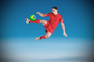 Naklejka premium Composite image of fit football player jumping and kicking
