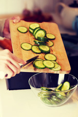 Caucasian attractive young woman is cutting cucumber.