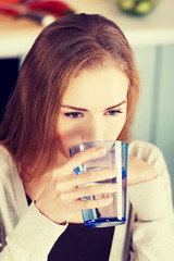 Beautiful caucasian woman sitting in the kitchen and drinking.