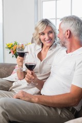 Happy mature couple with wine glasses in living room