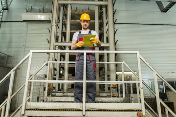 Man in a safety hat taking notes on a factory
