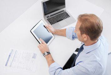 businessman with tablet pc and papers in office