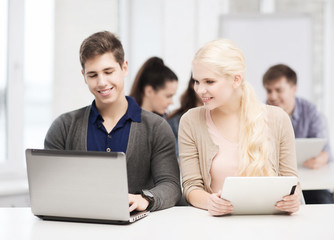 Fototapeta premium two smiling students with laptop and tablet pc