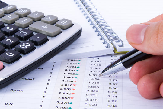 Hand Holding Pen and Analyzing Financial Data
