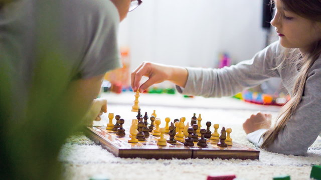 Two girls playing chess in room. film tilt.