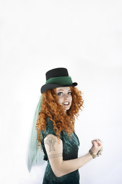 Woman wearing a top hat showing her tattoo of a Celtic cross.