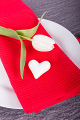 Teller mit weißer Tulpe, Herz und roter Serviette