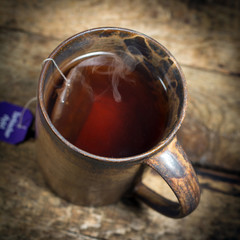 Tasse mit schwarzem Tee auf einem alten Holztisch