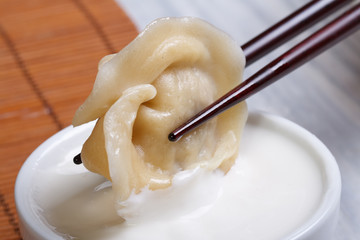 closeup dumpling with chopsticks in a white sauce