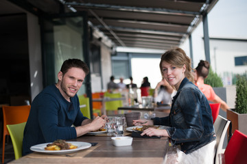 cheerful young couple having lunch outdoor in a restaurant