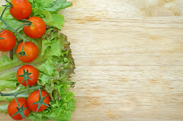 Fresh tomatoes and lettuce on wooden background