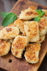 Fried chicken nuggets with mint leaves on a chopping board