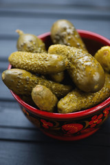 Close-up of a wooden khokhloma bowl with pickles, vertical shot