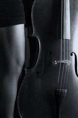 Beautiful brunette playing cello with selective light in black d