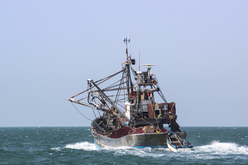 A fishing boat is at sea fishing.
