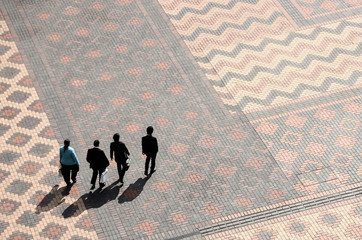Four business people walking through a square