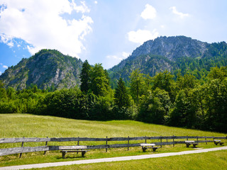 Fototapeta na wymiar wooden benches, green meadow and German Alps