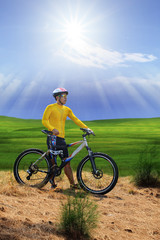Fototapeta premium young man standing beside moutain bike ,mtb on hill with sun shi