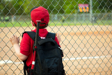 Young baseball player watching game from outside fence © Robert Hainer