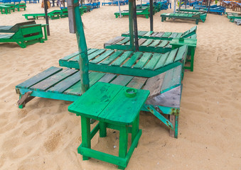 Group of empty green sunbeds at sandy beach.